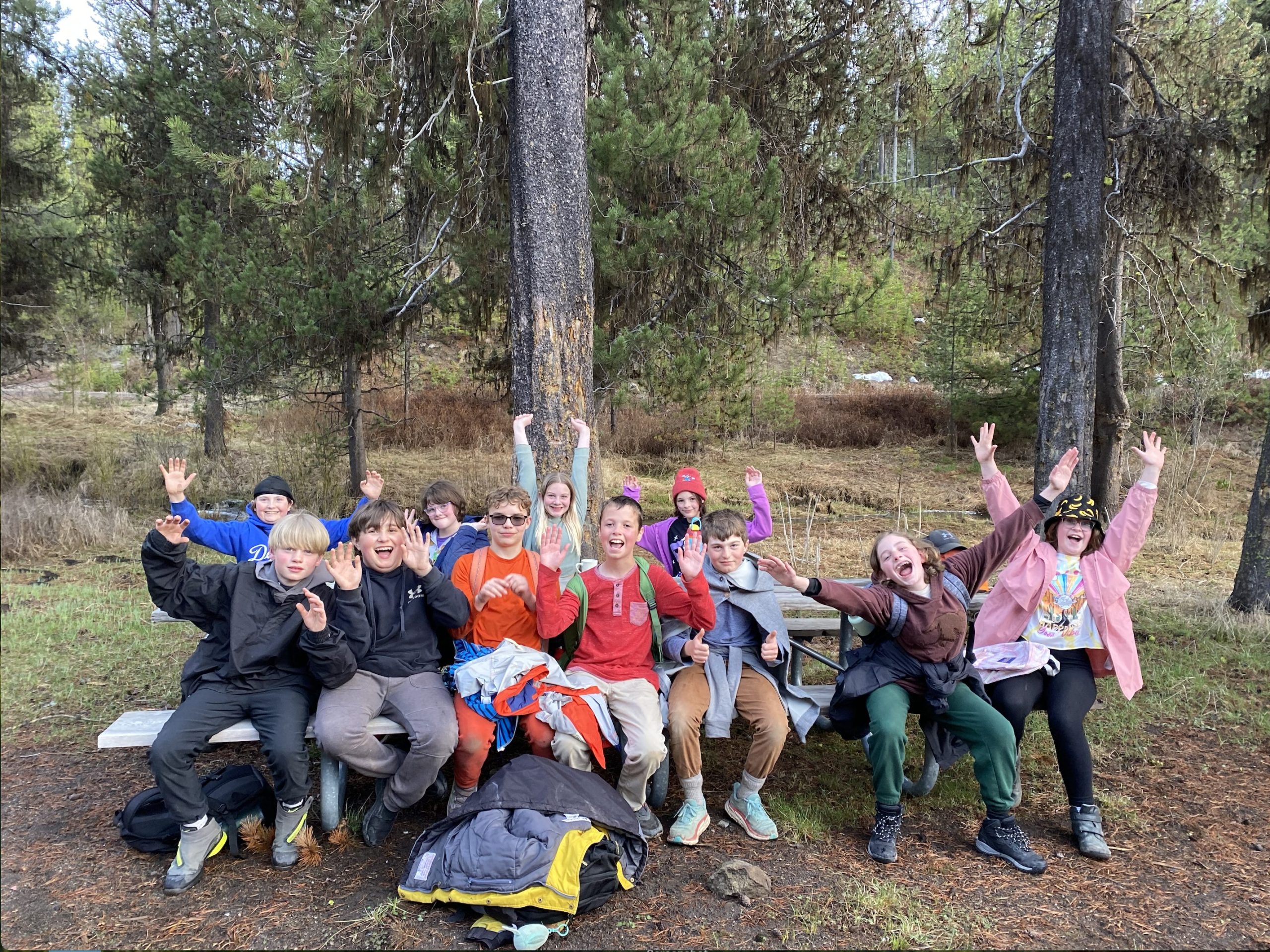 students waving from a forest